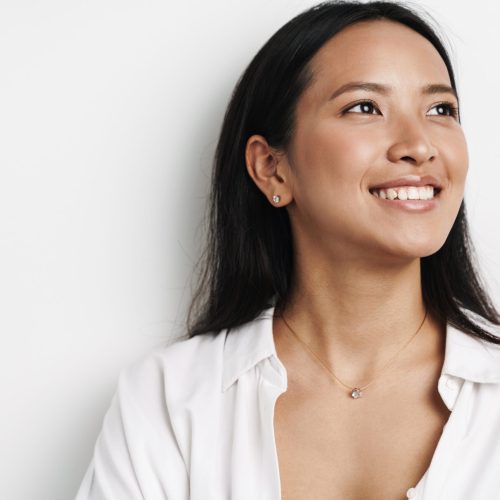 Beautiful happy asian woman smiling and looking aside isolated over white background
